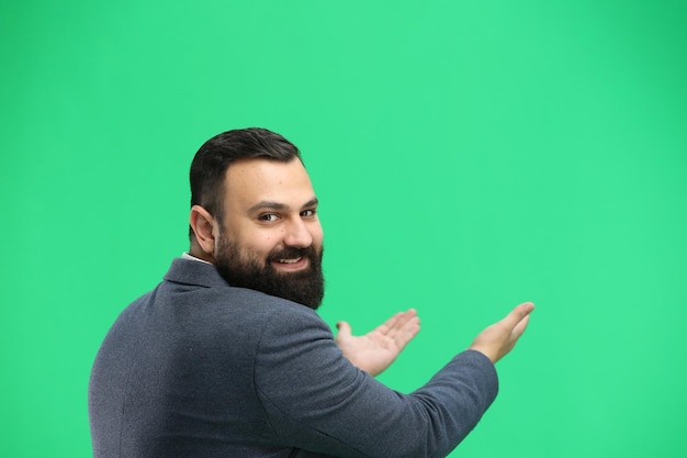 Un homme en gros plan sur un fond vert pointe vers l'avant