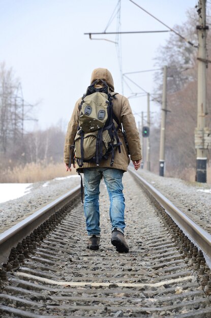 Un homme avec un gros sac à dos s&#39;en va sur la voie ferrée