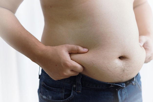 Photo homme avec gros ventre dans le concept de régime homme en surpoids touchant son gros ventre et veut perdre du poids