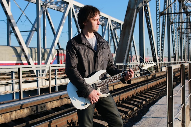 Homme avec une guitare sur un chemin de fer