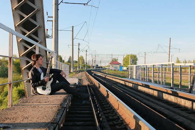 Homme avec une guitare sur un chemin de fer