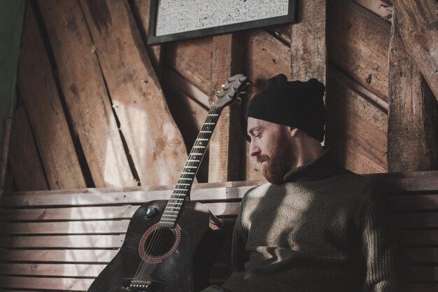 Photo un homme à la guitare contre un mur de bois