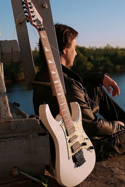 Un homme avec une guitare électrique dans le paysage industriel à l'extérieur