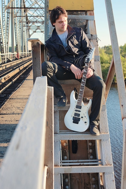 Un homme avec une guitare électrique dans le paysage industriel à l'extérieur