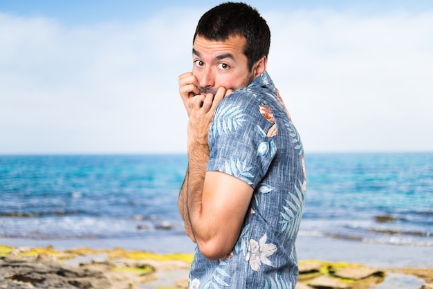 Homme habillé effrayé avec une chemise à fleurs à la plage