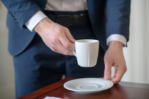 Homme habillé formellement tenant une tasse de café