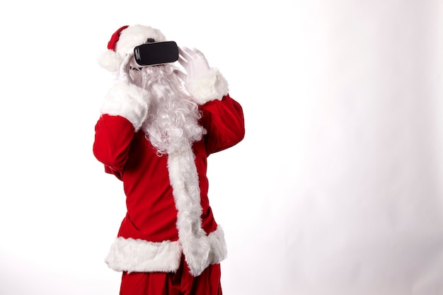 Homme habillé en Père Noël avec des lunettes de réalité virtuelle sur fond blanc