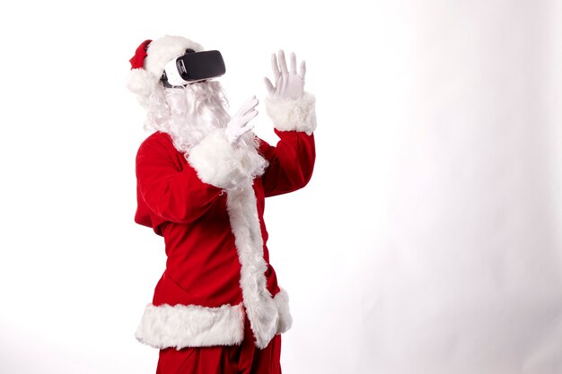 Homme habillé en Père Noël avec des lunettes de réalité virtuelle sur fond blanc