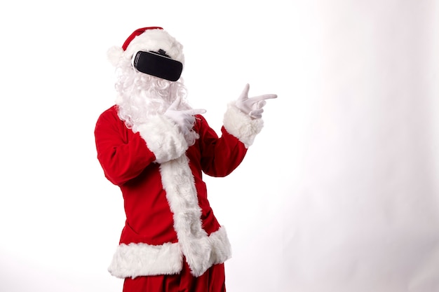 Homme habillé en Père Noël avec des lunettes de réalité virtuelle sur fond blanc