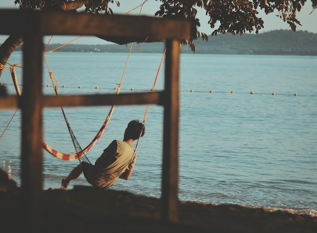 Photo un homme sur un hamac sur la plage contre le ciel