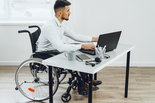 Homme handicapé dans un fauteuil roulant à l'aide d'un ordinateur portable close up