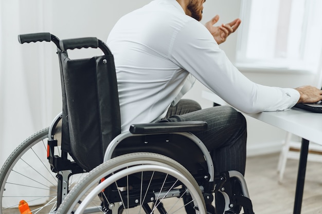 Homme handicapé dans un fauteuil roulant à l'aide d'un ordinateur portable close up