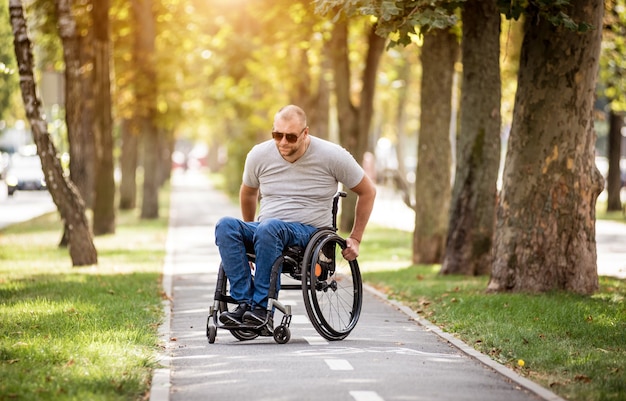 Homme handicapé en fauteuil roulant à pied à l'allée du parc