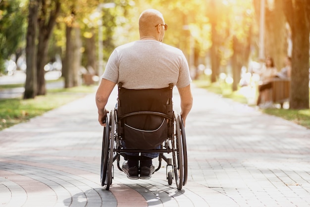 Homme handicapé en fauteuil roulant à pied à l'allée du parc