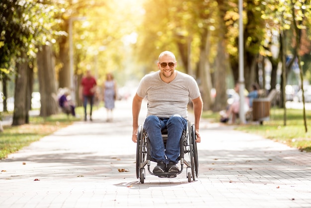 Homme handicapé en fauteuil roulant à pied à l'allée du parc