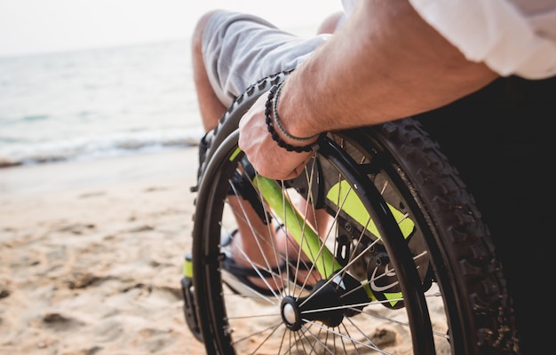 Homme handicapé en fauteuil roulant sur la plage.