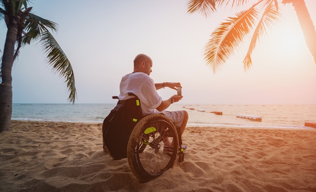 Homme handicapé en fauteuil roulant sur la plage.