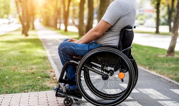 Homme handicapé en fauteuil roulant prépare à traverser la route sur un passage pour piétons