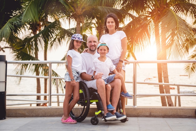 Homme Handicapé En Fauteuil Roulant Avec Sa Famille Sur La Plage.