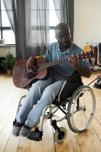 Homme handicapé jouant de la guitare à la maison