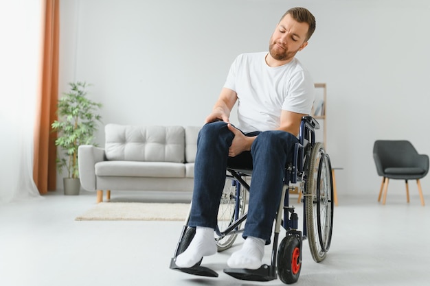 Un homme handicapé à la maison essaie de se mettre debout dans un fauteuil roulant Le concept de réadaptation après des blessures et des accidents de voiture