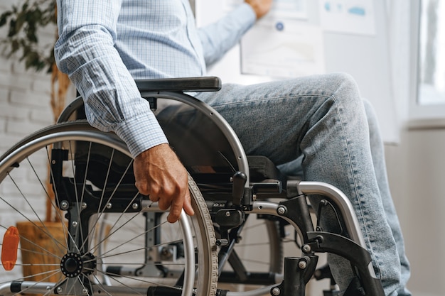 Homme handicapé méconnaissable assis dans un fauteuil roulant