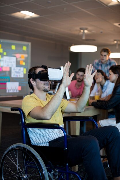 Homme handicapé physique en fauteuil roulant à l'aide d'un casque VR au bureau