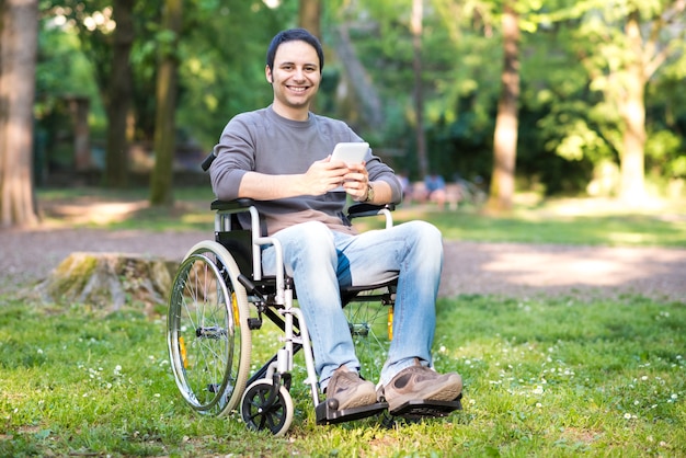 Homme handicapé souriant à l&#39;aide d&#39;une tablette dans un parc