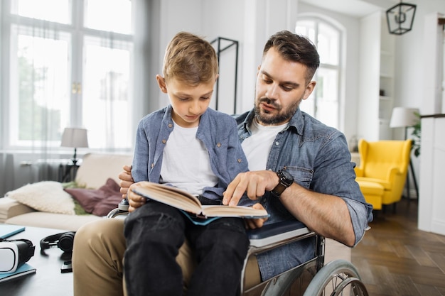 Homme handicapé tenant son fils à genoux et lisant un livre