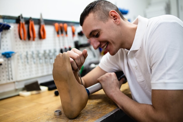 Homme handicapé travaillant dans un magasin d'amputés pour la production de pièces d'extrémité prothétiques.