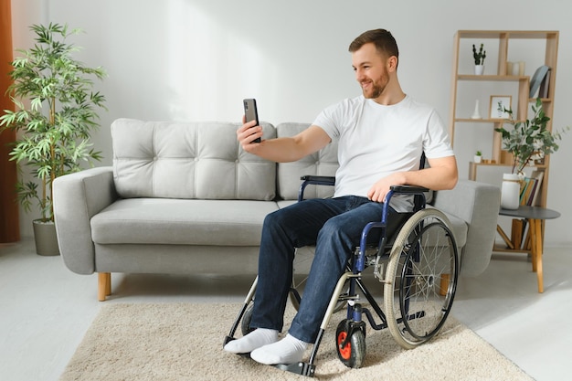 Homme handicapé utilisant un smartphone moderne pour une conversation vidéo tout en restant à la maison Concept de handicap et de technologie des personnes