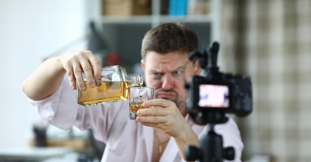 Homme avec un hématome sous l'œil versant de l'alcool et prenant une caméra vidéo