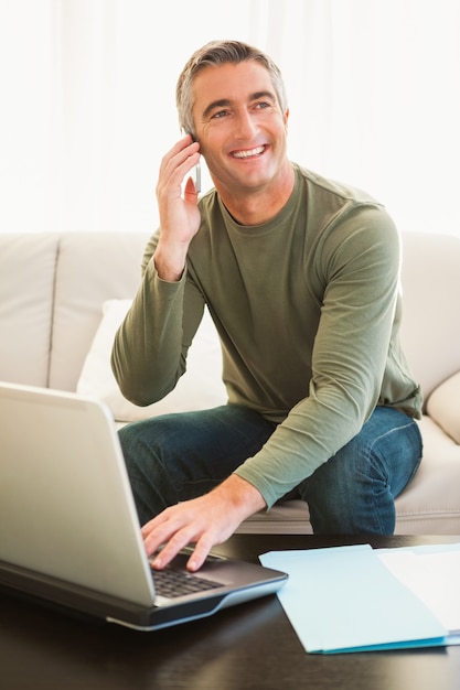 Homme heureux au téléphone à l&#39;aide d&#39;un ordinateur portable