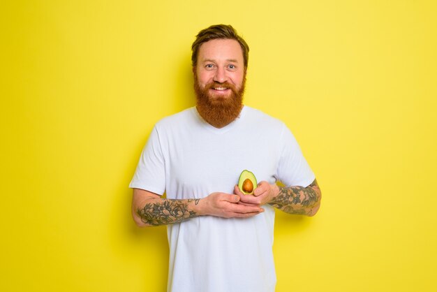 L'homme heureux avec la barbe et les tatouages tient un avocat