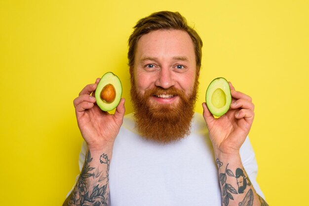 L'homme heureux avec la barbe et les tatouages tient un avocat