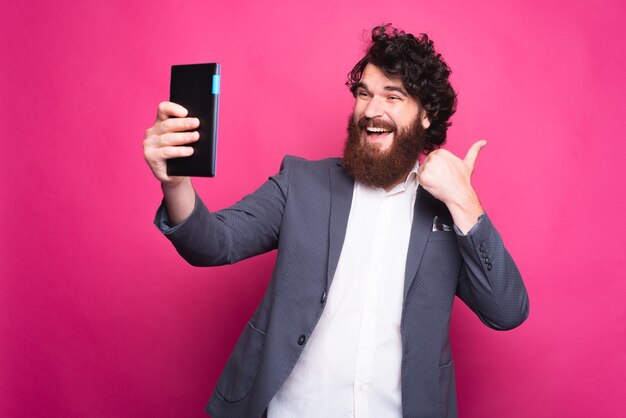 Homme heureux barbu prenant un selfie avec un tampon