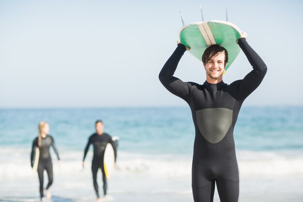 Homme heureux en combinaison de surf portant la tête