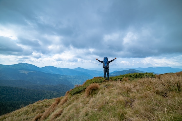 L'homme heureux debout sur la montagne sur fond de nuages pluvieux