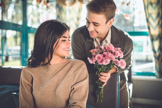 L'homme heureux donnant des fleurs à une femme dans le restaurant