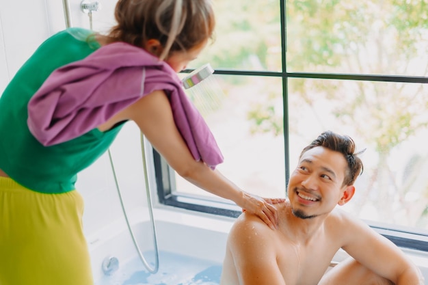 Photo un homme heureux, enfantin et drôle s'occupe de la douche de sa femme.