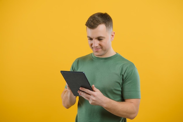 Un homme heureux et étonné utilisant une tablette numérique ayant l'air choqué par les nouvelles des médias sociaux, un consommateur d'acheteurs étonné surpris enthousiasmé par la victoire en ligne isolée sur fond jaune.