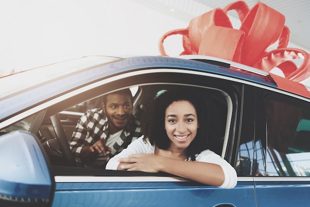 Un homme heureux fait un cadeau à une femme qui achète une voiture de rêve.