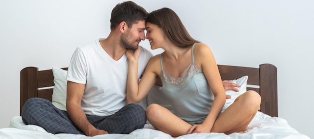 L'homme heureux et une femme assise sur le lit sur fond blanc