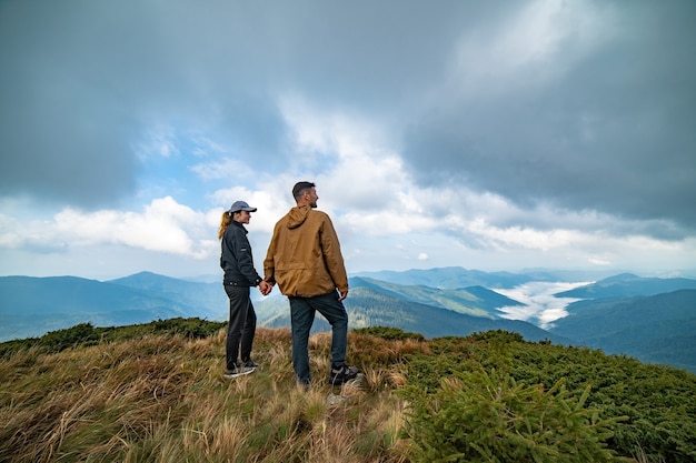 L'homme heureux et une femme debout au sommet d'une montagne