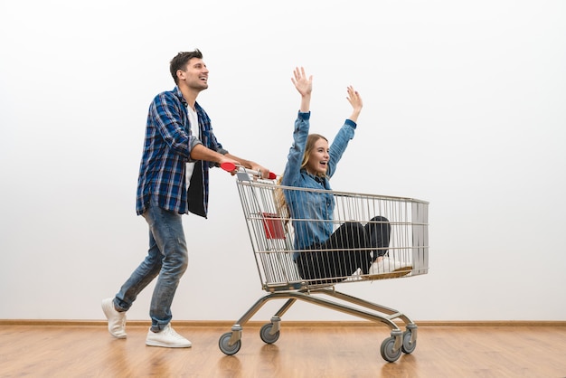 L'homme heureux et une femme montent sur le chariot sur un fond de mur blanc