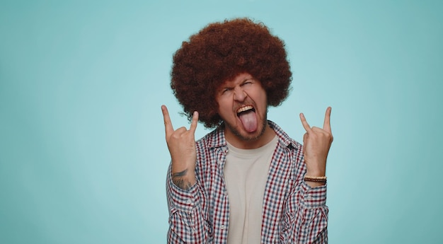 Un homme heureux et heureux montrant un geste de rock'n'roll par les mains un signe cool criant oui avec un visage fou