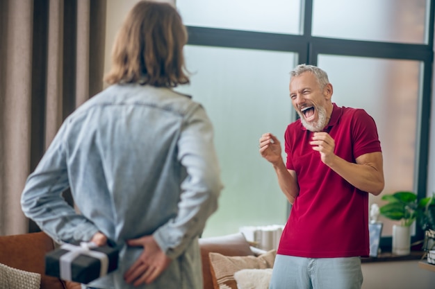 Homme heureux. Homme aux cheveux gris à heureux de recevoir un cadeau de son partenaire