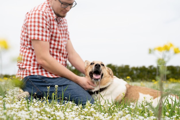 Un homme heureux joue avec un chien de berger de race mixte sur une mise au point sélective d'herbe verte