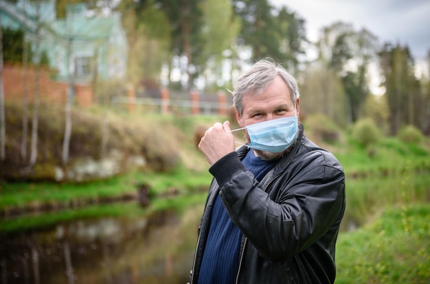 Homme heureux lors d'une promenade dans la nature au bord de la rivière L'homme enlève le masque médical de son visage