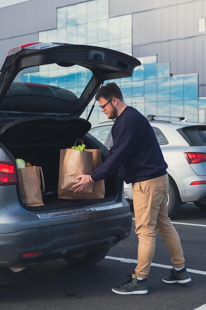 L'homme heureux a mis le sac d'épicerie dans le coffre de la voiture.